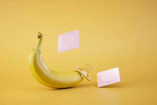 protection of the body from diseases and unwanted pregnancy. banana with condoms on a yellow background. 3D render.