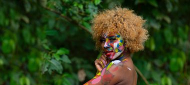 Nueva Loja, Sucumbios / Ekvador - 3 Eylül 2020: Odaklanmamış yeşil bir arka planda, şehvetli bir ifadeyle başını çeviren, arkası boyalı siyah bir kadının portresi