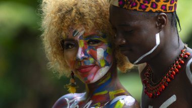 Nueva Loja, Sucumbios / Ekvador - 3 Eylül 2020: Odaklanmamış yeşil arka plana sahip bir ormanda boyalı vücuda aşık siyah bir çiftin portresi