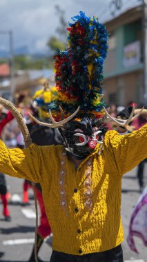 Pillaro, Tungurahua / Ekvador - 5 Ocak 2024: Pillaro kentindeki Diablada Pillarena 'da siyah ve sarı bir şeytan gibi giyinmiş insan portresi
