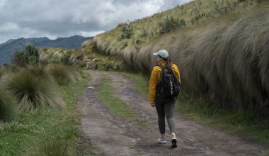Güzel Latin Amerikalı bir kadın güneşli bir günde sırt çantasıyla dağdaki toprak bir patikada yürüyor.