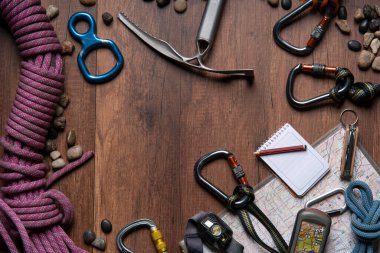 Tırmanma ekipmanları, halat, karabinalar, buz baltası, harita, GPS, far, çakı ve defter ile ahşap masa üst görünümü