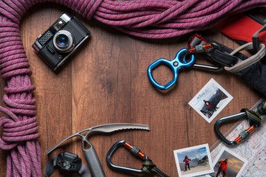 Tırmanma ekipmanları, halat, karabinalar, buz baltası, harita, far, cep çakısı, not defteri ve zirvedeki adamın fotoğraflarıyla dolu klasik kamera.