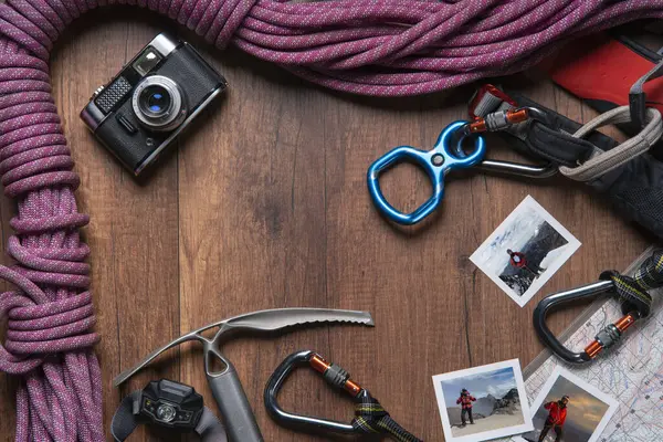 Tırmanma ekipmanları, halat, karabinalar, buz baltası, harita, far, cep çakısı, not defteri ve zirvedeki adamın fotoğraflarıyla dolu klasik kamera.