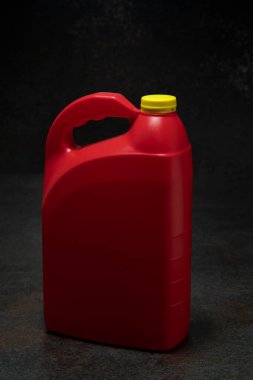 Kırmızı plastik motor yağı şişesinin dörtte üçü saplı ve sarı vida kaplamalı koyu seramik ve siyah arkaplan