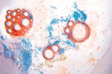 Su damlaları, yağ, mavi ve turuncu mürekkep içeren soyut bileşim beyaz arka planda