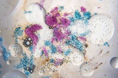 Su, kabarcıklar, yağ damlaları ve beyaz arka planda mavi ve mor mürekkep lekeleri ile soyut bileşim