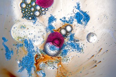 Su damlaları ile soyut bileşim, yağ ve mavi, turuncu ve mor mürekkep lekeleri beyaz arka planda