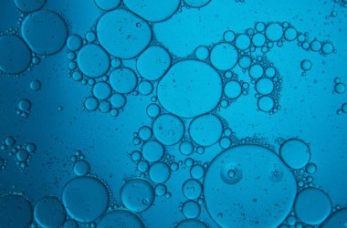 Mavi arka planda su ve yağ damlalarıyla soyut bileşim