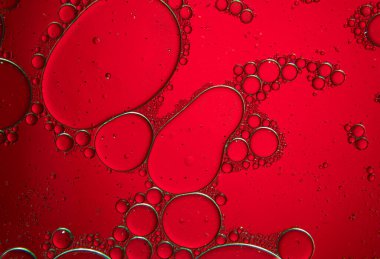 Su ve yağ damlaları ile soyut bileşim ve kırmızı zemin üzerinde yeşil ışık