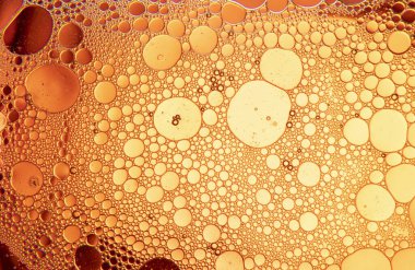 Sarı ve turuncu arka planda su ve yağ damlalarıyla soyut bileşim