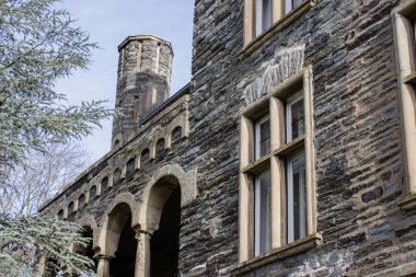 Süslü bir balkonu ve temiz gökyüzüne karşı tarihi bir kulesi olan ortaçağ taşından kale cephesi.