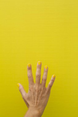 Tırnakları sarıya boyanmış, beş parmağı da sararmış bir kadının dikey fotoğrafı..