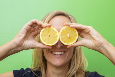 Kırklı yaşlarda, limonun iki yarısı kadar sarışın bir kadın gözlerini ağzı açık kapatıyor. Yatay fotoğraf