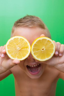 7 yaşında, sarışın bir çocuk. İki doğal limonla gözlerini kapatmış. Ağzı açık, yeşil bir arka planda çığlık atıyor..