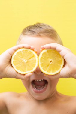 7 yaşında, sarı arka planda ağzı açık bağıran iki doğal limonlu sarışın bir çocuk..