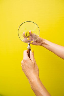 Zar sarı bir arka planın arkasındaki büyüteçten baktı.