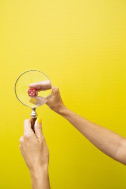 Kırmızı zarlar sarı bir arka planın arkasındaki büyüteçten baktılar.