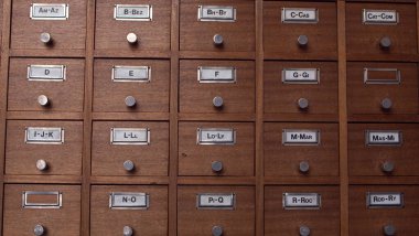 Kahverengi ahşap çekmeceler antikacı arşivinde alfabetik sıraya göre ayrılmış.