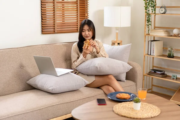 Női Vállalkozó Nagy Kényelmes Kanapén Kenyeret Eszik Miközben Laptop Párnára — Stock Fotó