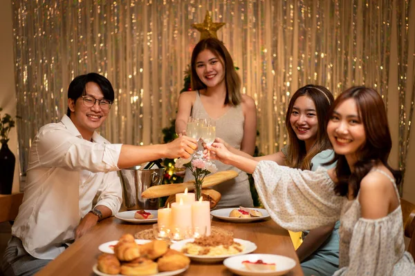 stock image Young people clinking with glass of champagne to celebrate and toasting with happiness while dinner in holiday of new year party at home.