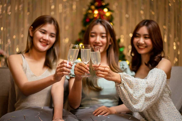 Young beautiful people sitting on the couch and clinking glass of champagne to toasting with happiness while celebrating in new year party at home.