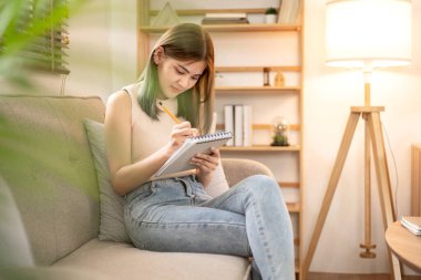 Rahat koltukta oturan kadın moda sanatçısı atölyede çalışırken yeni moda tasarımları, çizimler ya da çizimler yapıyor..