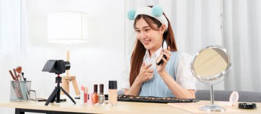 Genç Güzellik Etkilendirici, sosyal medyada veya stüdyoda web blogcusu paylaşımı için kameraya video kaydederken kozmetik ürünlerini test etmek ve tavsiye etmek için toz ürünü gösteriyor.