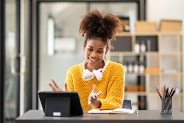 Afrika kökenli Amerikalı bir kız öğrenci, üniversitede eğitim ve öğrenim görürken online ders çalışmak ve sınıf arkadaşlarıyla sohbet etmek için tablet üzerine video konferansı düzenliyor..