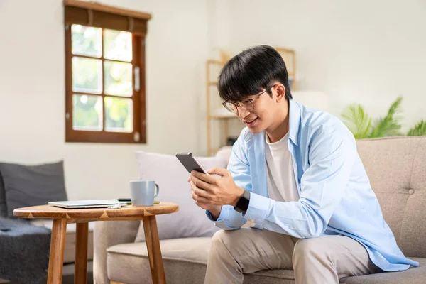 stock image Businessman in casual is sitting on comfortable sofa and chatting business information with colleague on smartphone while working in living room at home.
