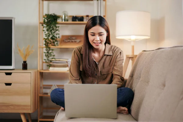女企业家在家里的客厅里坐在舒适的大沙发上 一边阅读新的商业项目 一边在笔记本电脑上输入数据 — 图库照片