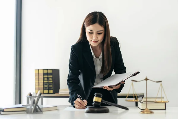 持有商业合同的女商业律师在律师事务所工作时 用黄铜刻度和司法锤在桌子上看书和写文件数据 — 图库照片
