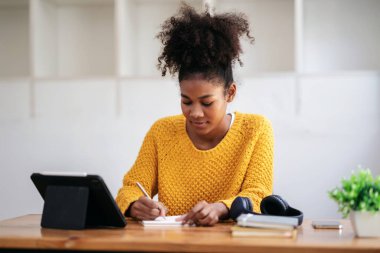 Kazaklı Afro-Amerikalı bir kadın, e-posta ile tablet dersine hazırlanıyor ve masada oturmuş, üniversitede öğrenim ve öğrenim görürken not alıyor..