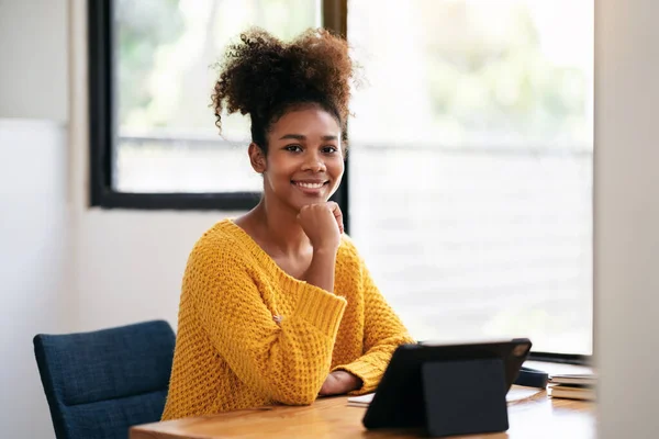 stock image African american student woman in sweater using digital tablet to watching e-learning and studying lesson online class while sitting on the desk to learning knowledge and education in university.