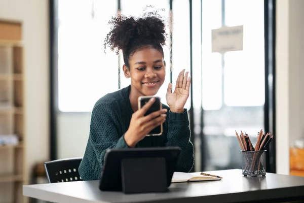 stock image African american student woman in sweater video conference on smartphone to studying lesson online class and greeting with classmates while sitting to learning knowledge and education in university.