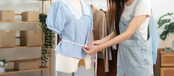 女性ファッションデザイナーは マネキンにドレスをフィッティングし 測定テープを使用してシャツを測定しながら スタジオで服の新しいコレクションを設計しています — ストック写真