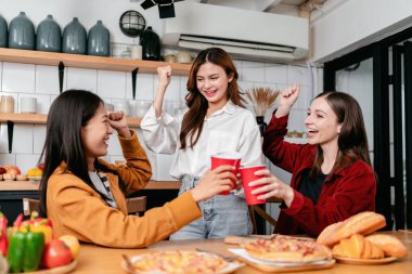 Bir grup arkadaş evde mutfaktaki partide eğlenirken ve kollarını kaldırırken birlikte bir bardak içki içip İtalyan pizzası yiyorlar..