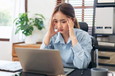 İş kadını dizüstü bilgisayarda bilgi okurken baş ağrısı ve stresli hissediyor ve modern ofiste yeni bir iş projesiyle ilgili muhasebe hakkında düşünceli davranıyor..