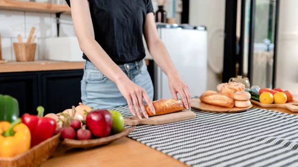 妇女在木制切菜板上切面包 在桌上准备新鲜蔬菜和水果 在家里的现代厨房为健康的早餐做饭 — 图库照片