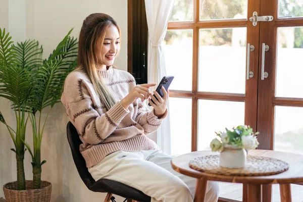Businessman in casual is thoughtful of idea for new business while sitting on the chair in living room to using smartphone to working and checking information of business project at home.