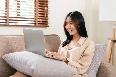 Kadın girişimci büyük rahat bir koltukta oturuyor ve evinde çalışırken iş verilerini daktilo etmek için yastığa koyuyor..