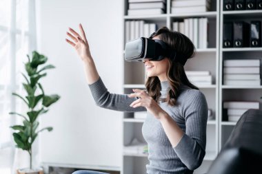 VR yaşam tarzı kavramına sahip iş kadını, oyun oynarken VR kulaklık takan iş kadını, çalıştıktan sonra teknolojiyle rahatlarken sanal gerçekliği yaşamak için havaya dokunuyor..