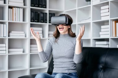 VR yaşam tarzı kavramına sahip iş kadını, oyun oynarken VR kulaklık takan iş kadını ve çalıştıktan sonra teknolojiyle rahatlarken sanal gerçekliğe dokunuyor..