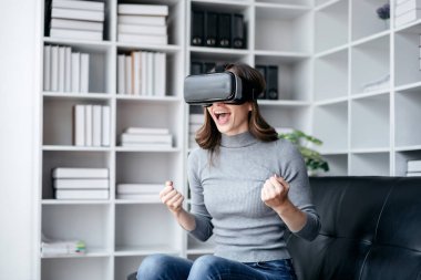 VR yaşam tarzı kavramına sahip iş kadını, oyun oynarken VR kulaklık takan iş kadını ve çalıştıktan sonra teknolojiyle rahatlarken sanal gerçekliğe dokunuyor..