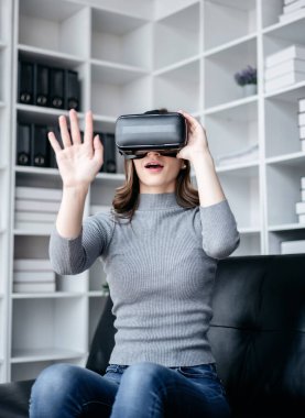 VR yaşam tarzı kavramına sahip iş kadını, oyun oynarken VR kulaklık takan iş kadını, çalıştıktan sonra teknolojiyle rahatlarken sanal gerçekliği yaşamak için havaya dokunuyor..