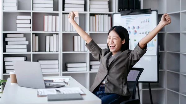 会计行业的理念 会计女性在与商业规划金融打交道的同时 一边兴奋地举起拳头 一边在笔记本电脑上看到好消息 一边庆祝自己的成就 — 图库照片