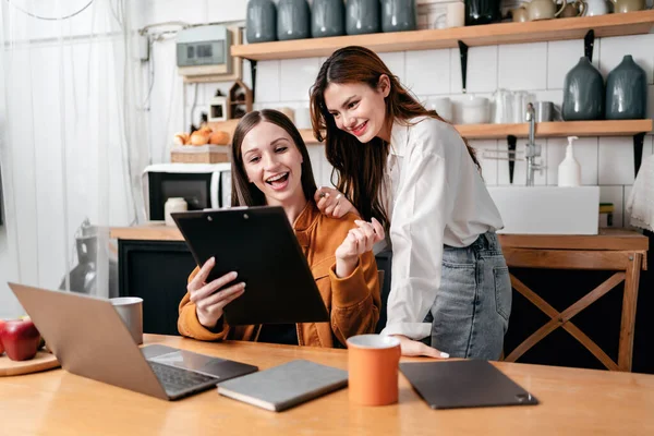 两名年轻妇女一起阅读剪贴板上的商业信息 在家里和桌上的笔记本电脑一起工作时 集思广益 讨论新的项目 — 图库照片