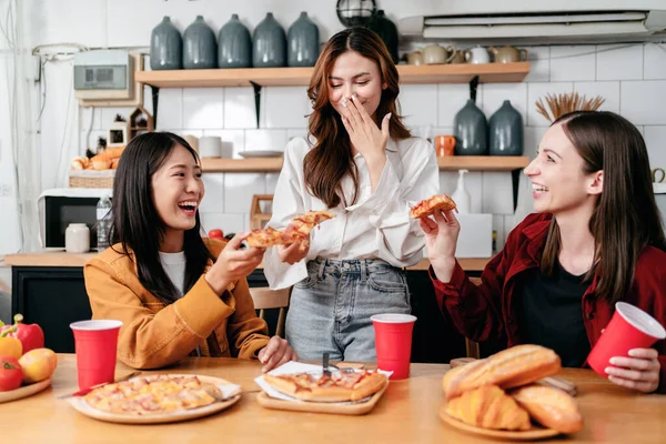 一群朋友一边吃意大利比萨饼一边聊天和大笑 一边和大家一起在家里的厨房庆祝周末 — 图库照片