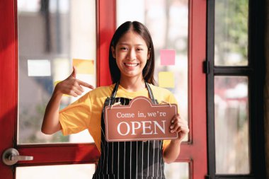 Kafe ve restoran açık konseptli küçük işletmeler, kafe girişinin yanında duran kadın girişimciler ve restoran müşterilerine kahve ve yemek servisi için hazır olduklarına dair açık tabelalar..