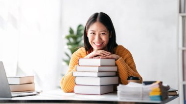Uzaktan eğitim konsepti, süveter giyen ve kitap okurken sırıtan ve evde eğitim dersi alan genç bir kadın..
